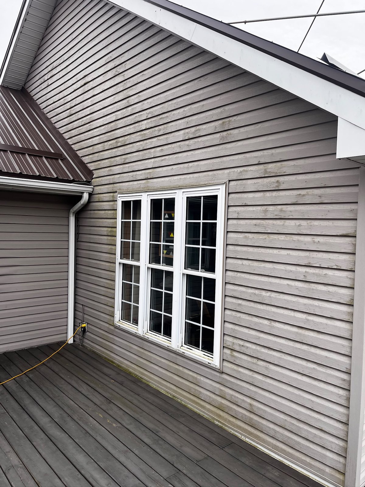 Grey siding and deck boards on a lakeside home before cleaning