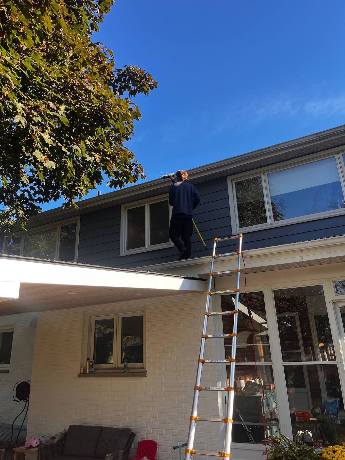 Clearing the roof edge from a ladder on a bright fall day