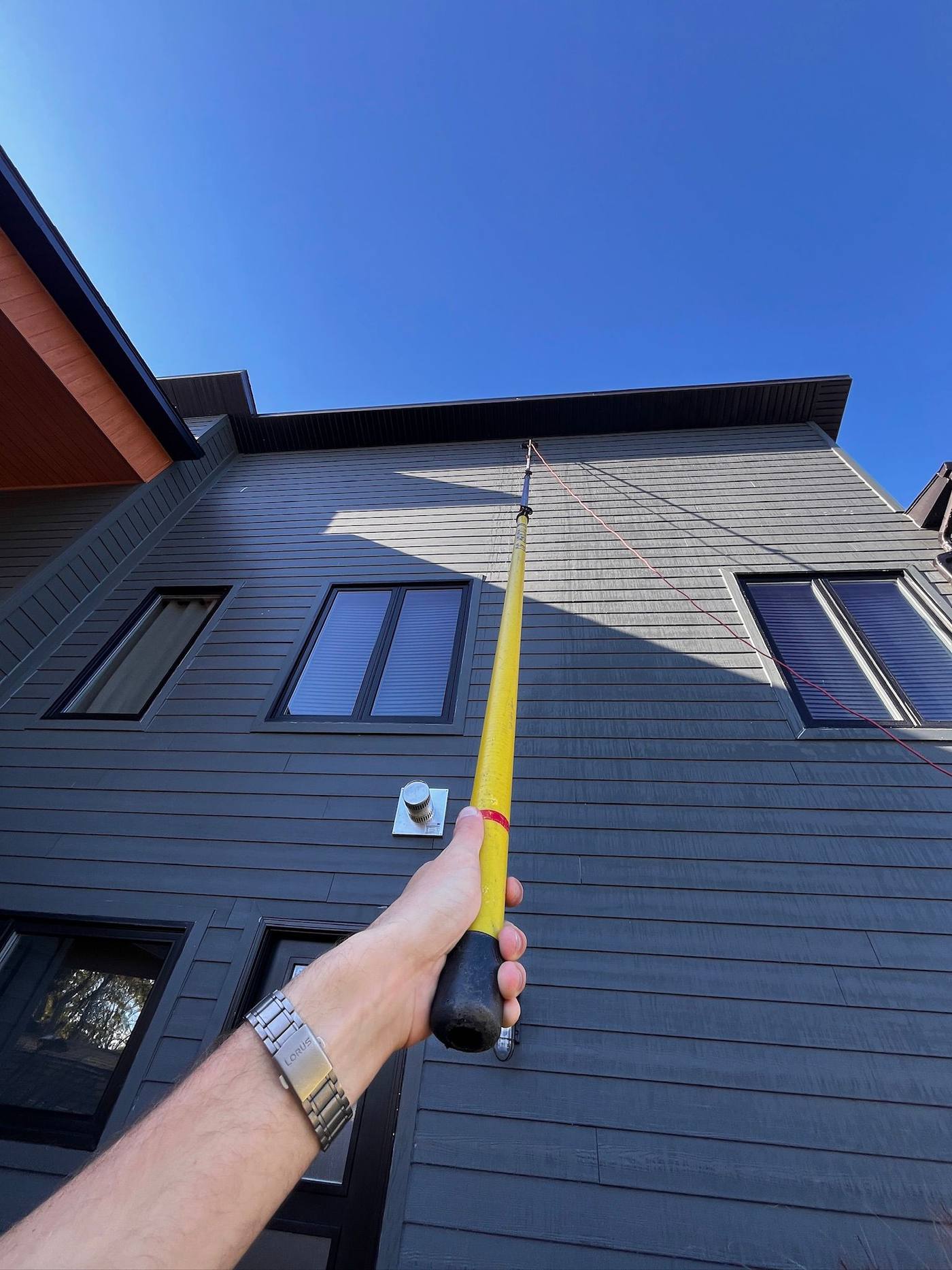 Water-fed pole up blue siding on a bright day