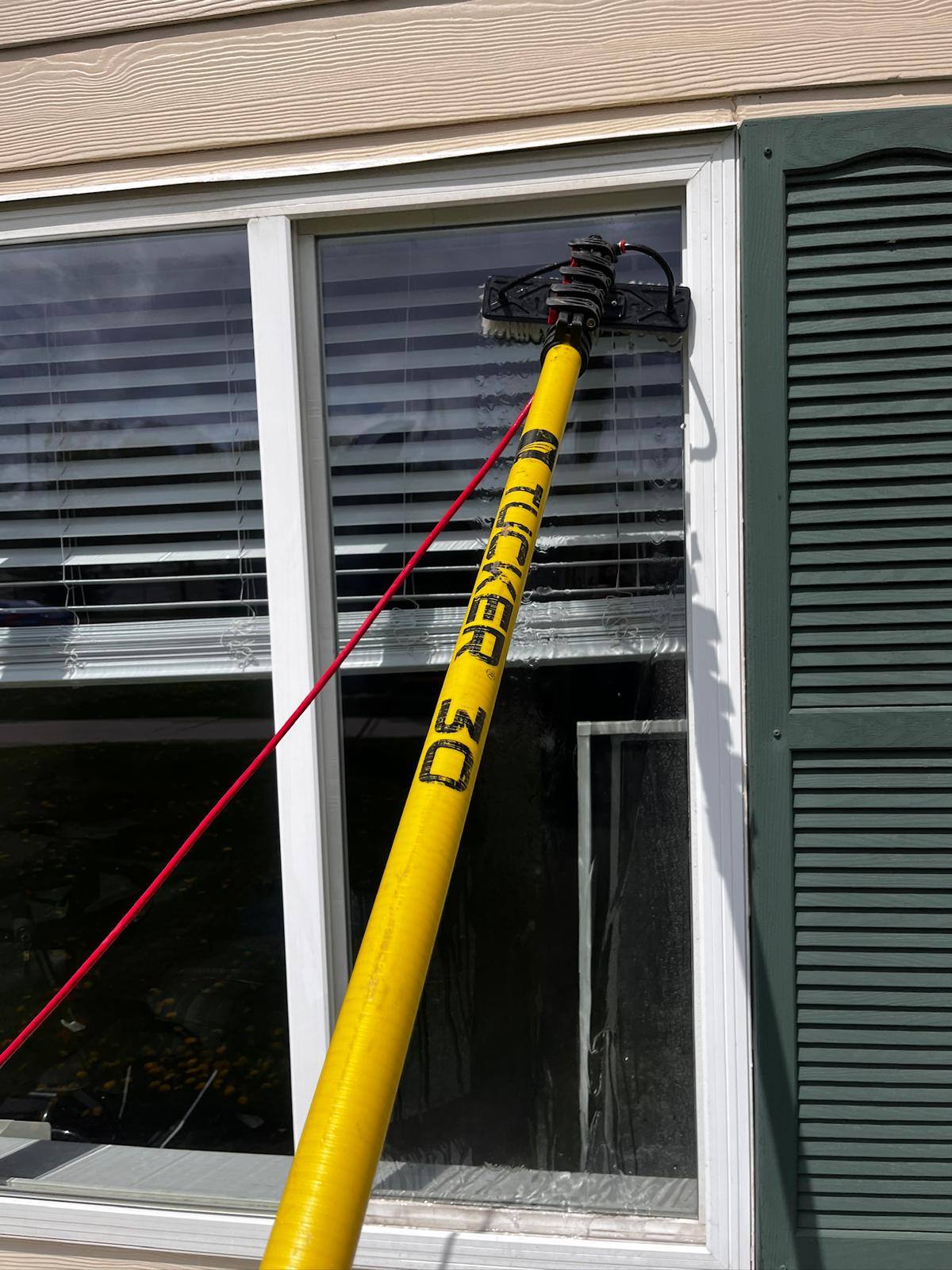 Water-fed pole cleaning a window between shutters