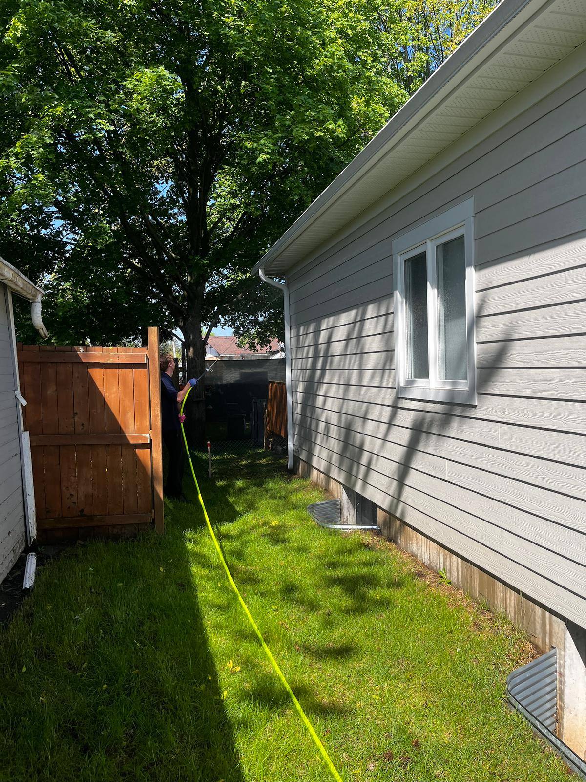 Rinsing down the side of a house after a soft wash