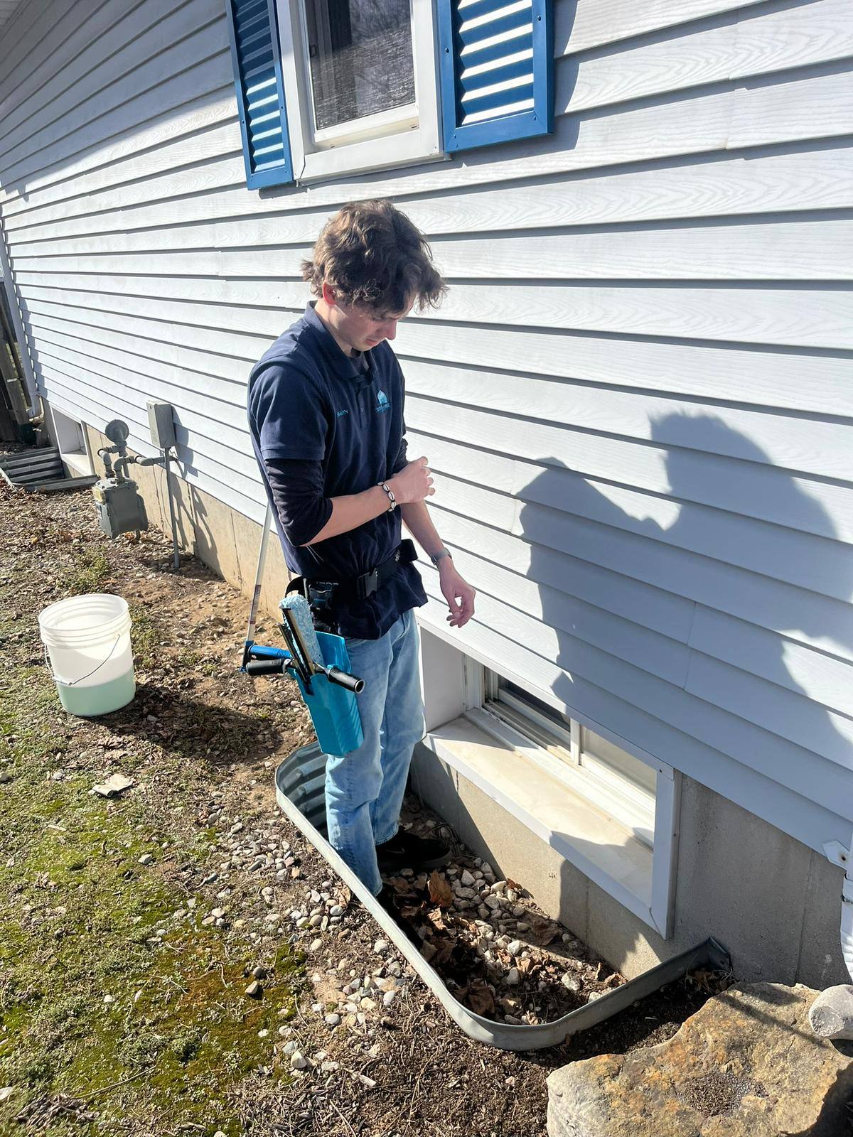 Cleaning a basement window with a bucket and cloth