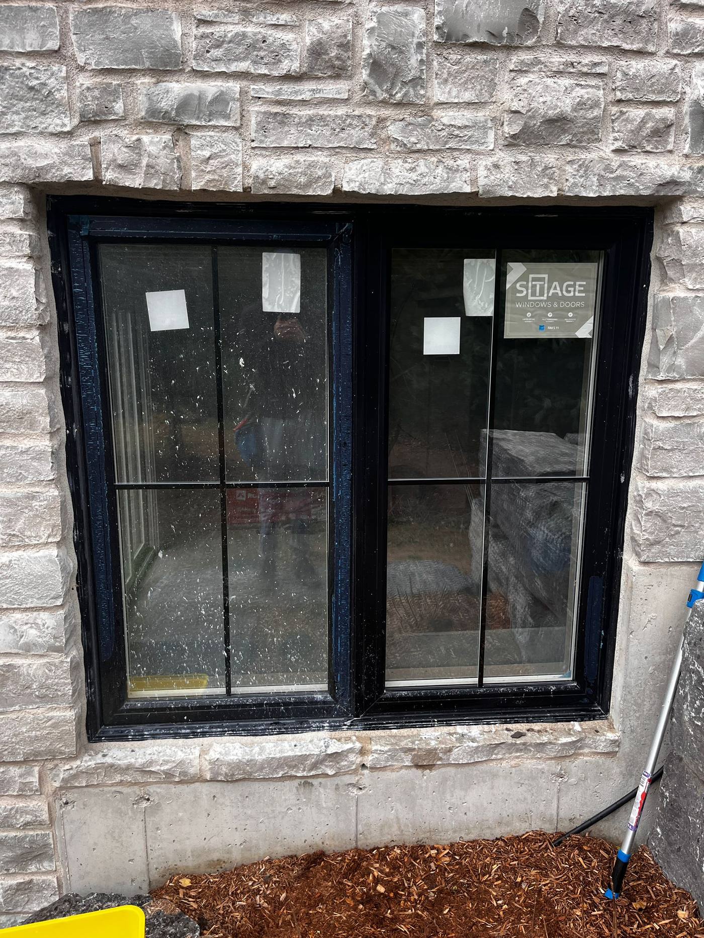 New-build window still carrying its manufacturer sticker and paint spatter, before a post-construction clean
