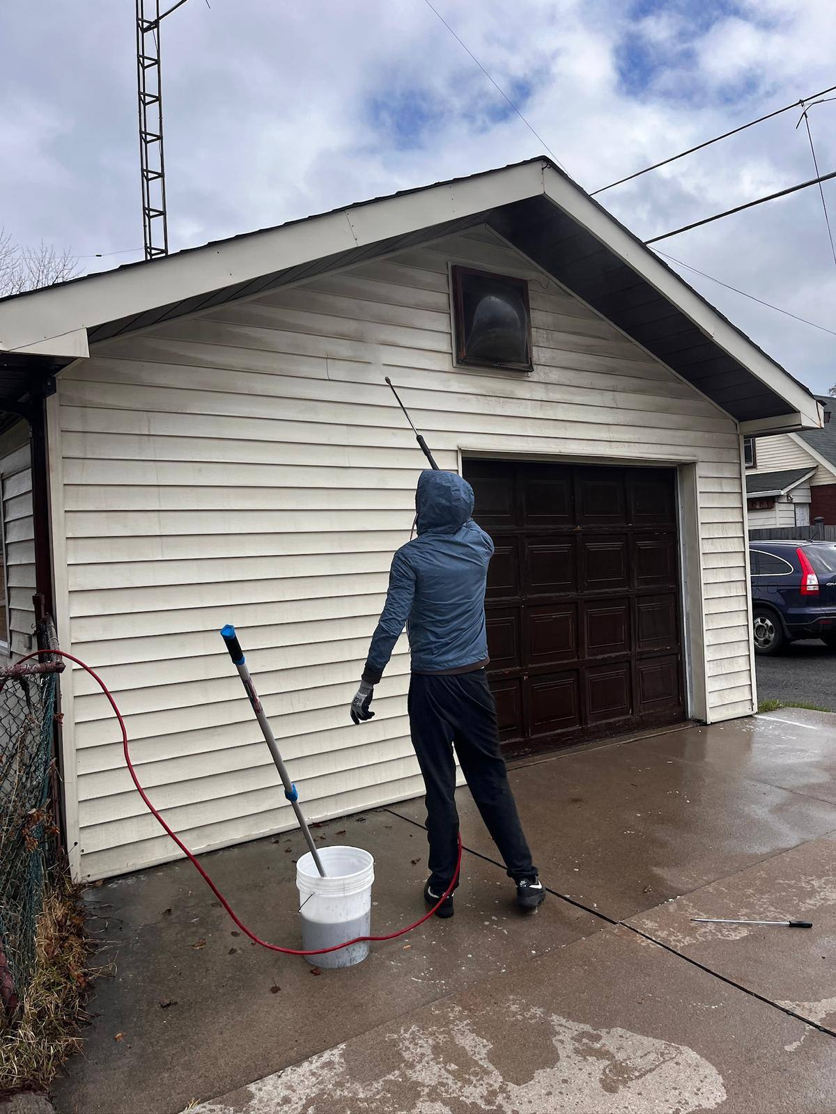 Pressure washing the driveway apron in front of a garage