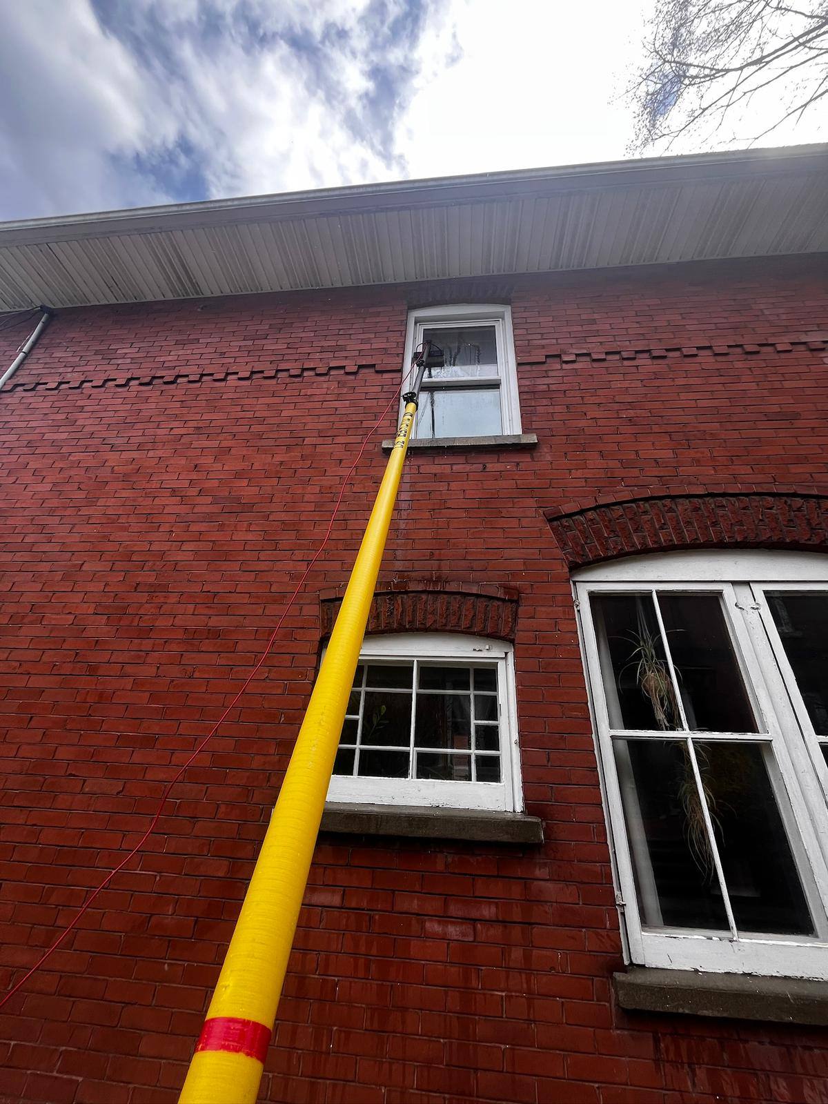 Water-fed pole up a red brick building