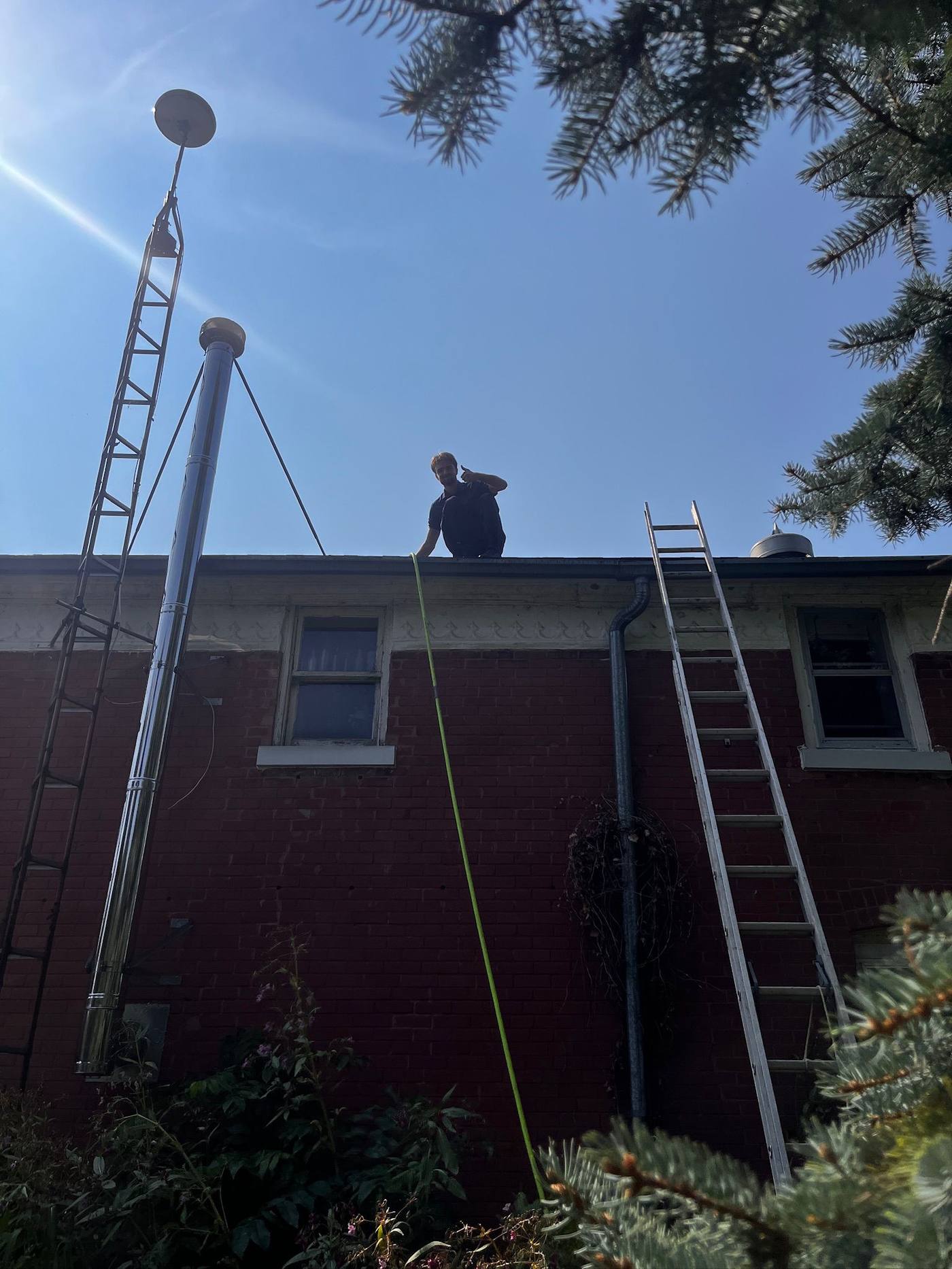 Owner on the roof beside the ladder, working along the eavestrough
