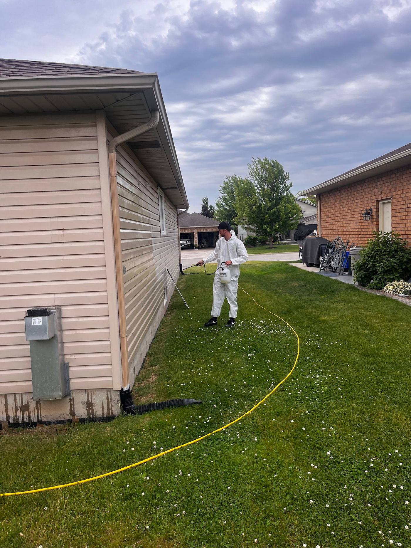 Soft washing the side of a house in protective gear